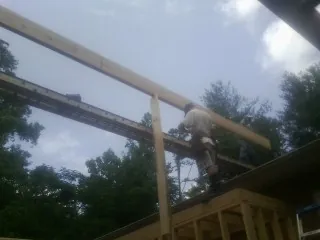 Carpenter setting a ridge beam over a new addition frame — Ice Dam Removal by Roofing Brothers in Locust