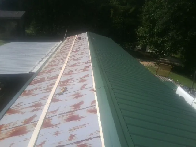 Old rusted panels beside newly installed green metal roofing — Wind Damage Roof Repair by Roofing Brothers in Locust