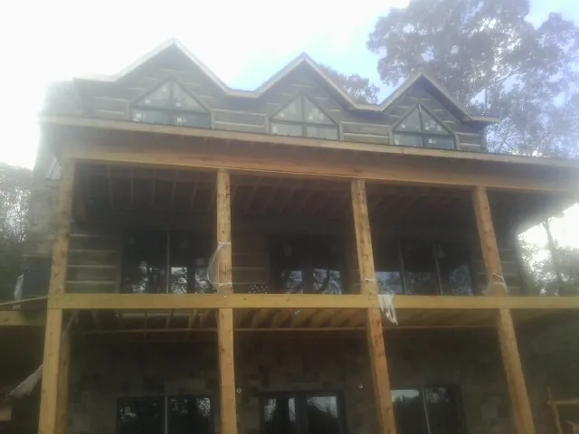 Dormers and porch framing on a large log home under construction — Roof Coating work by our crew in Locust