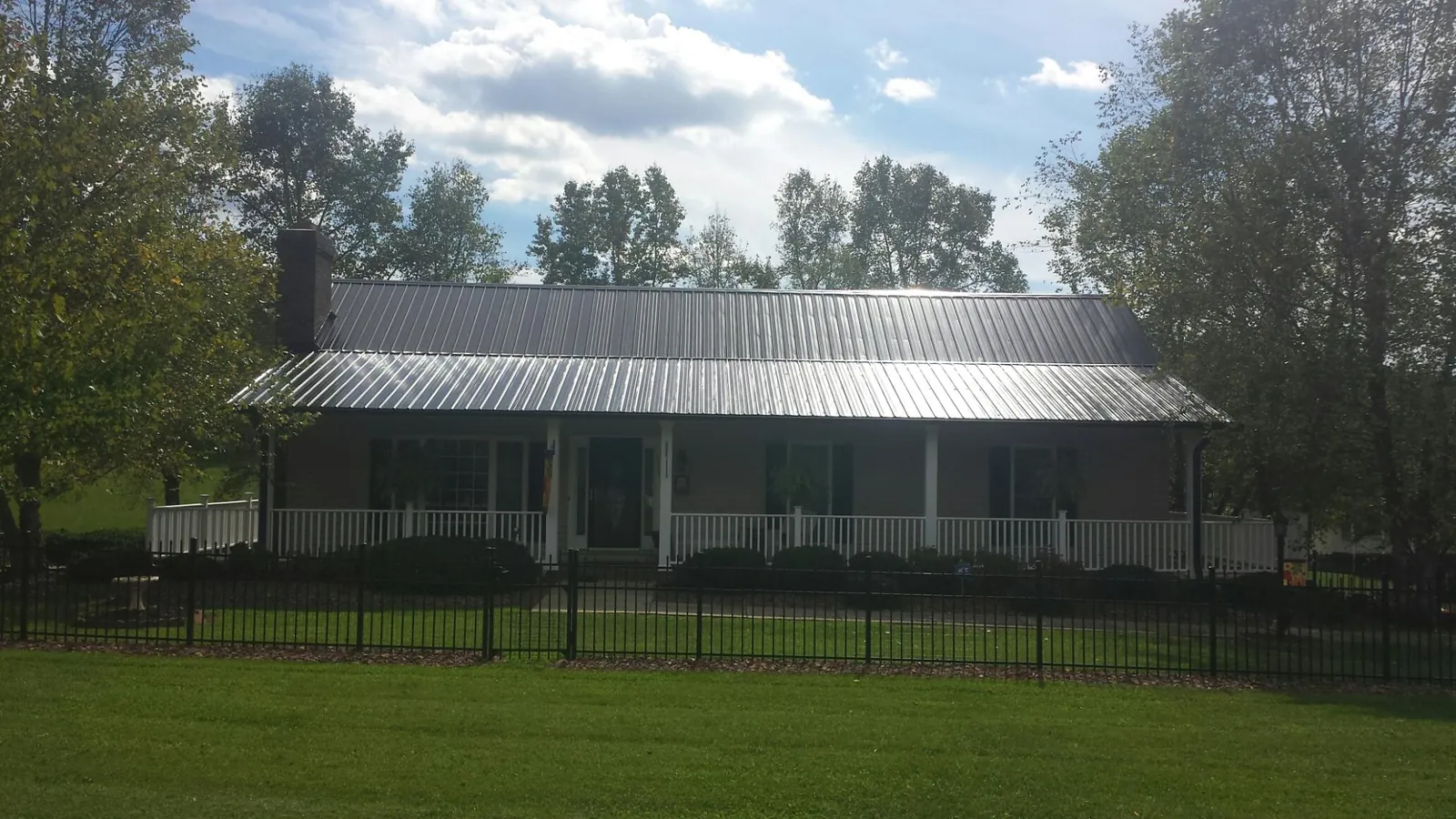 Gray metal roof on a brick ranch with a full width front porch — Gutter Guard Installation work by our crew in Locust